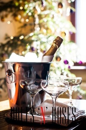 Luxury holiday composition, a bottle of chilled champagne in an ice bucket and vintage glasses, festive lights in the background